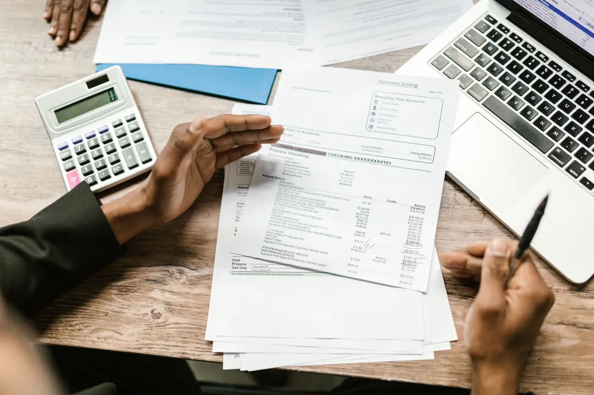 Manos revisando facturas y documentos tributarios junto a una calculadora