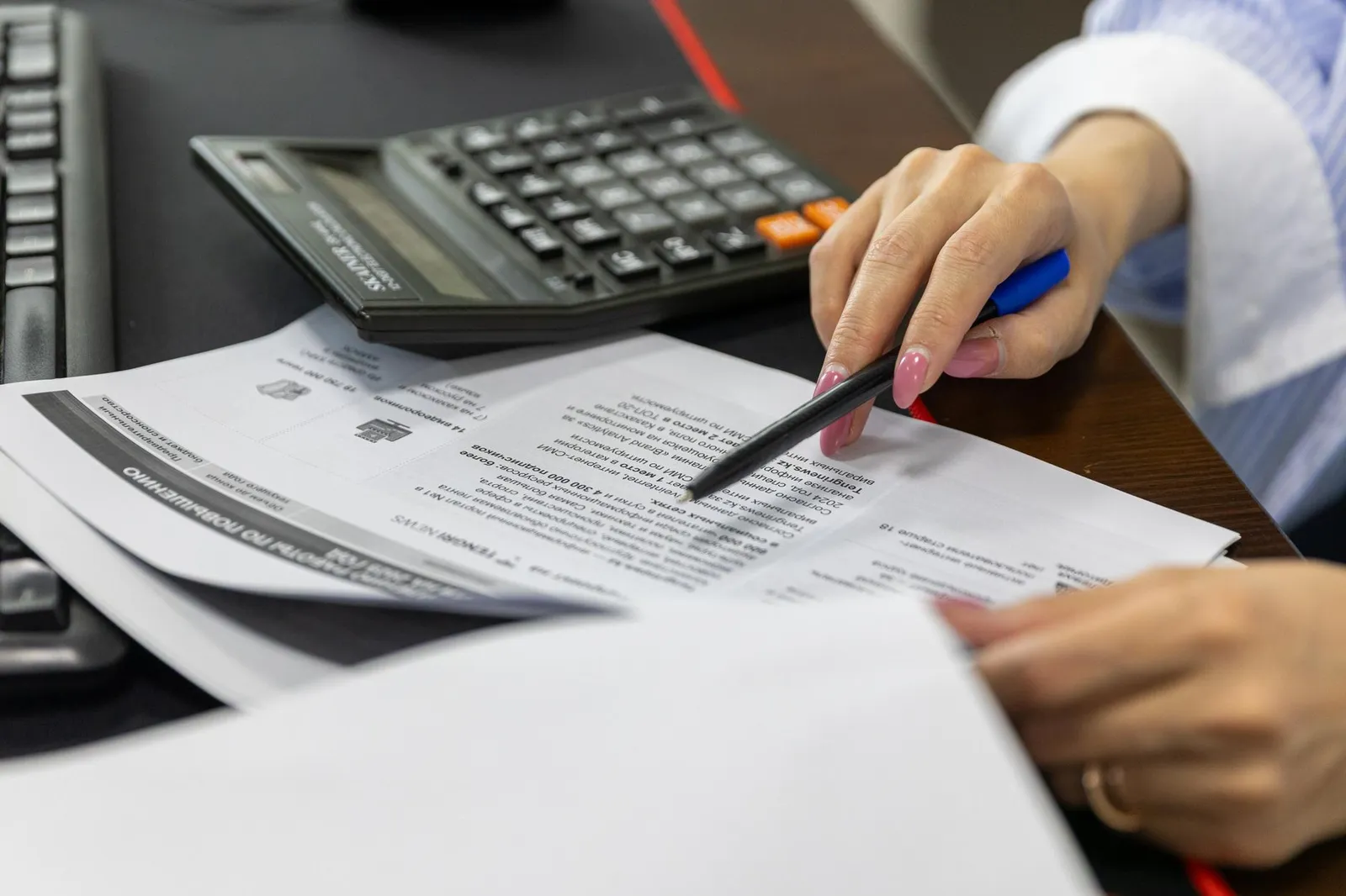 Revisión profesional de estados financieros con calculadora sobre un escritorio
